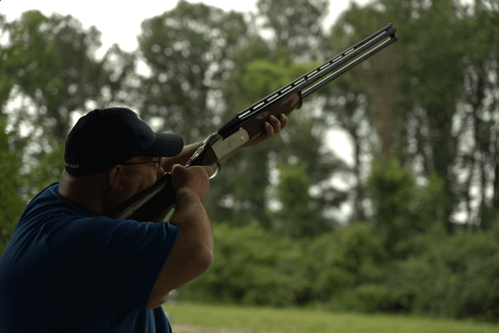 a man aiming a shotgun at a sporting clays course